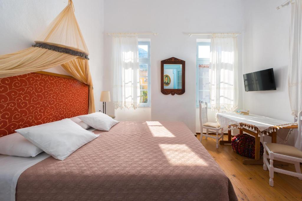 a bedroom with a large bed and a desk at Castello Venetsiana in Symi