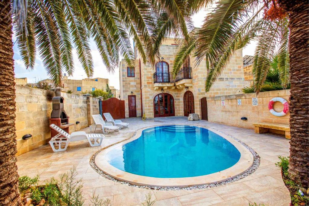 a swimming pool in a yard with a palm tree at Il-Palma Holiday Farmhouse with Sunny Private Pool in Island of Gozo in Għarb