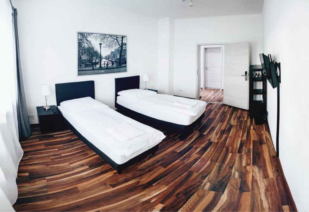 twee bedden in een kamer met een houten vloer bij Bedroom in Neurenberg