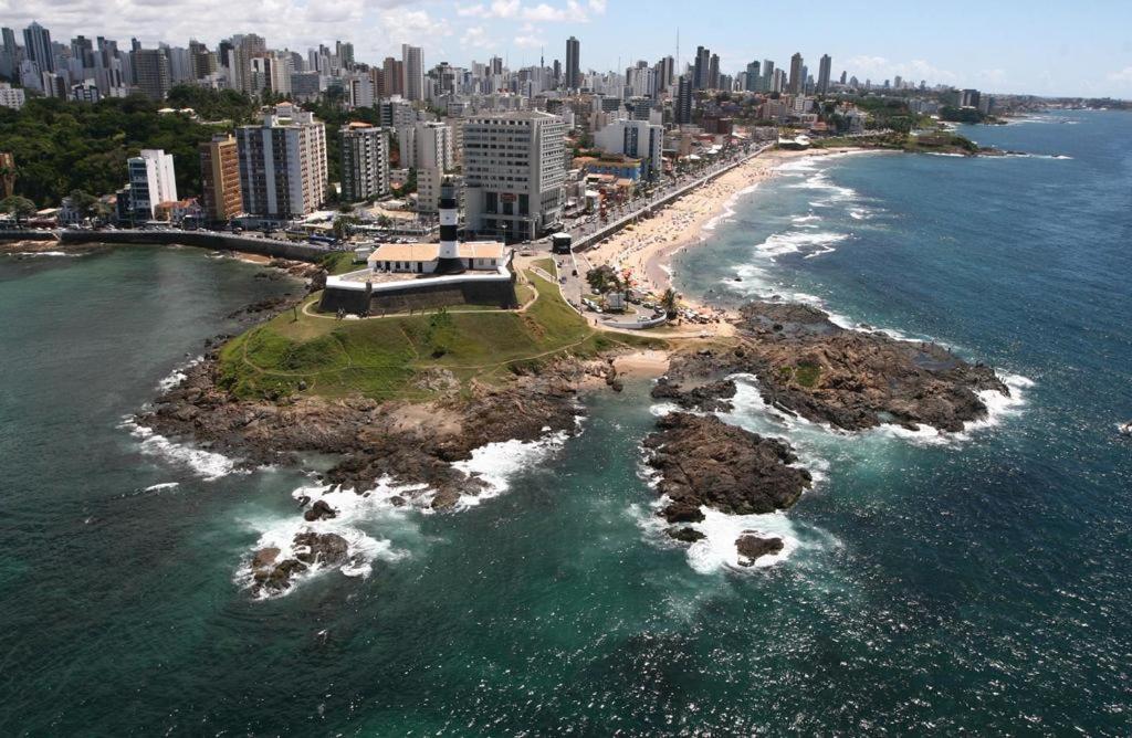 an island in the ocean next to a city at Flat à Beira Mar na Barra in Salvador