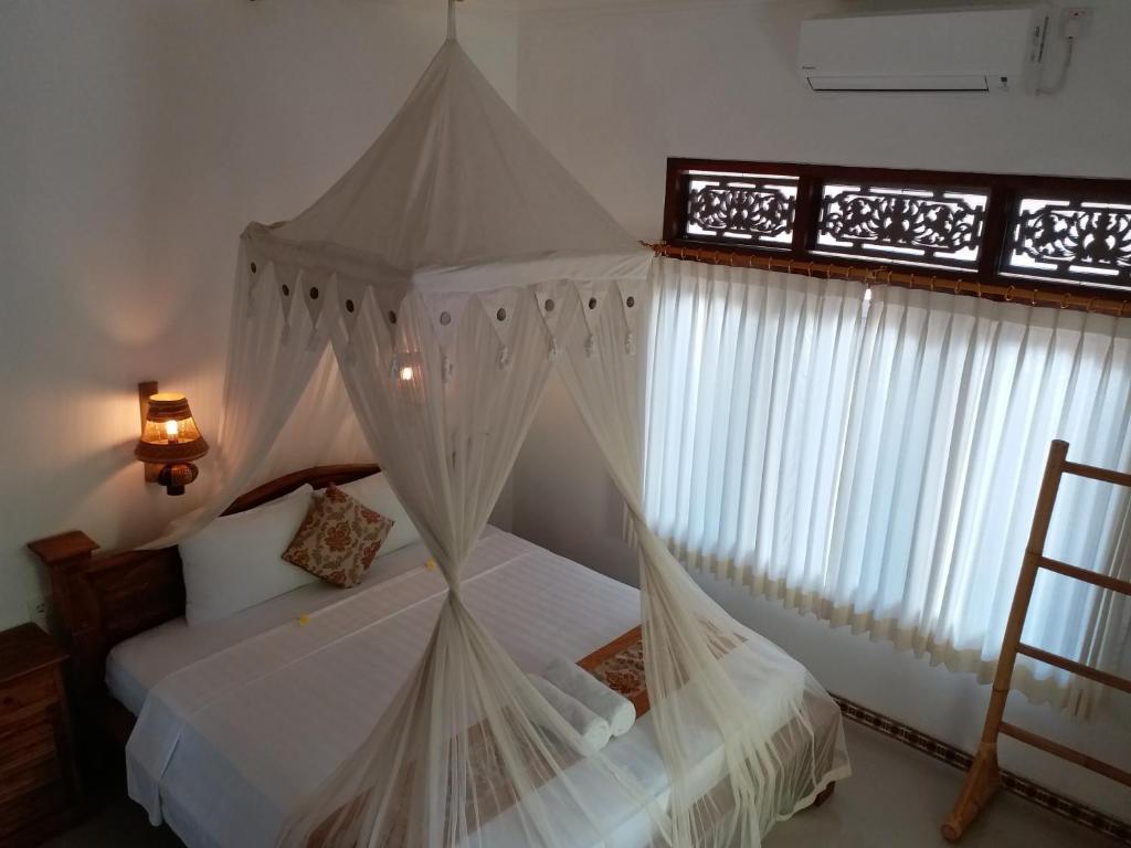a bedroom with a canopy bed with white curtains at Praety Home Stay in Ubud