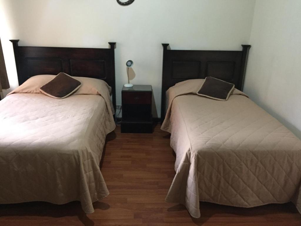 1 dormitorio con 2 camas y mesa con lámpara en Comfort Hostel en Guatemala