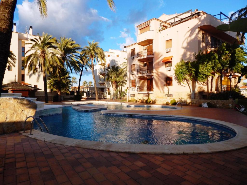 - une piscine en face d'un bâtiment avec des palmiers dans l'établissement Estudio el Retiro, à Dénia