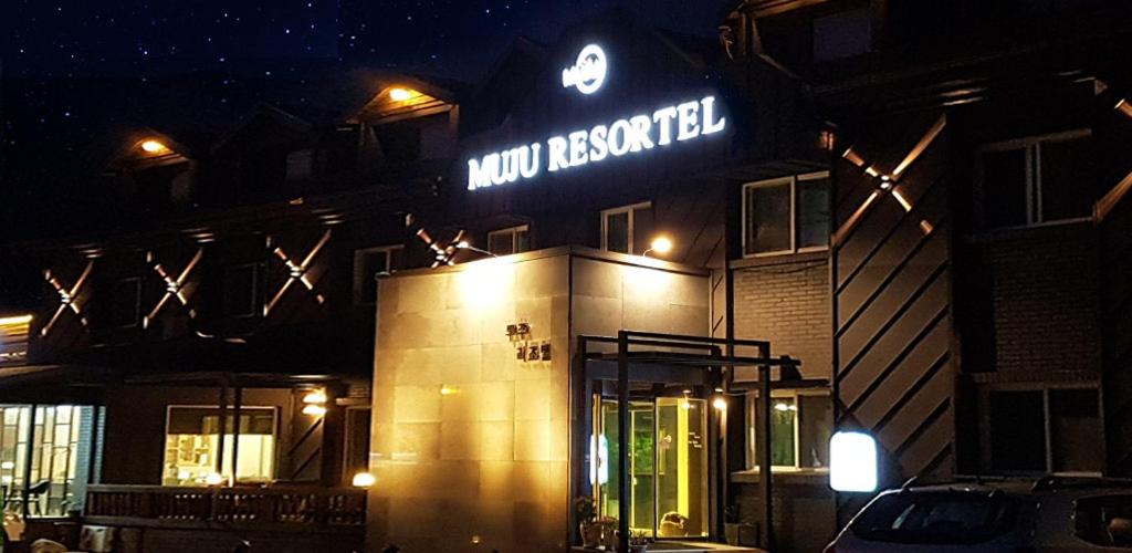 a building with a neon sign on it at night at Muju Rejortel in Muju