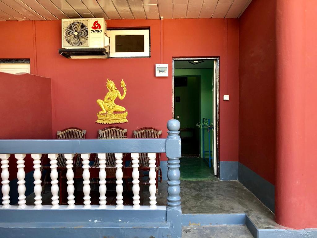 a red wall with a door with a statue on it at Golden Myanmar Guest House in Bagan