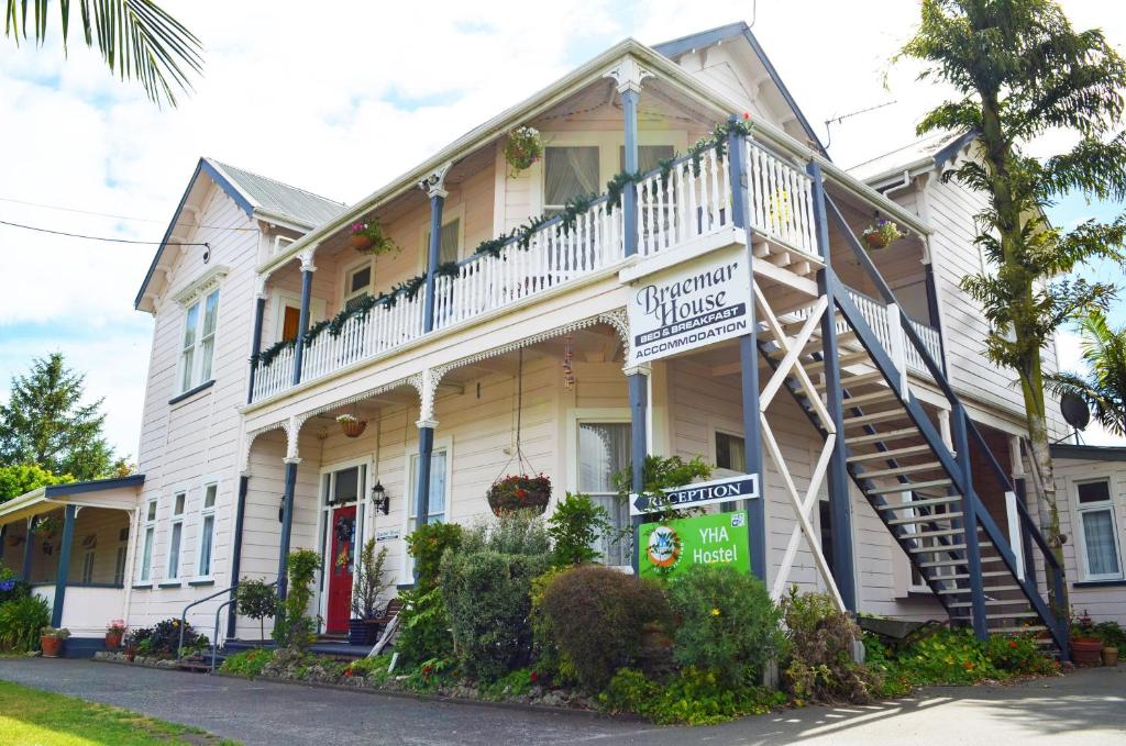 een wit huis met een veranda en een balkon bij Braemar House B&B and YHA Hostel in Whanganui