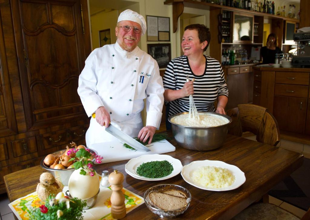 Ein Mann und eine Frau stehen in einer Küche und bereiten Essen vor. in der Unterkunft Hotellerie Waldesruh in Oberlimberg