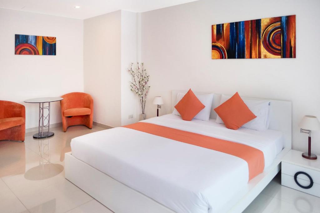 a white bedroom with a large bed with orange pillows at Sunny Beach Residence in Jomtien Beach