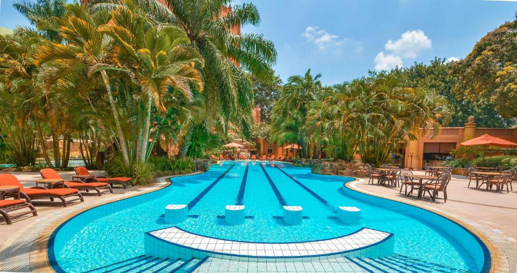 a pool at a resort with tables and chairs at Kampala Serena Hotel in Kampala