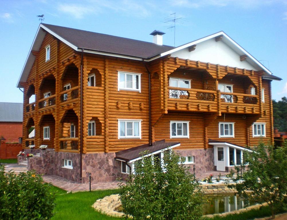 a large wooden house with a balcony on top at Mustang Guest House in Izhevsk