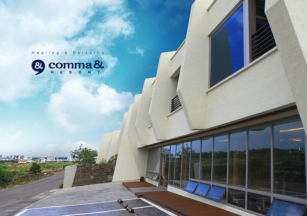 a building with a sign on the side of it at Comma&Spa Resort in Seogwipo