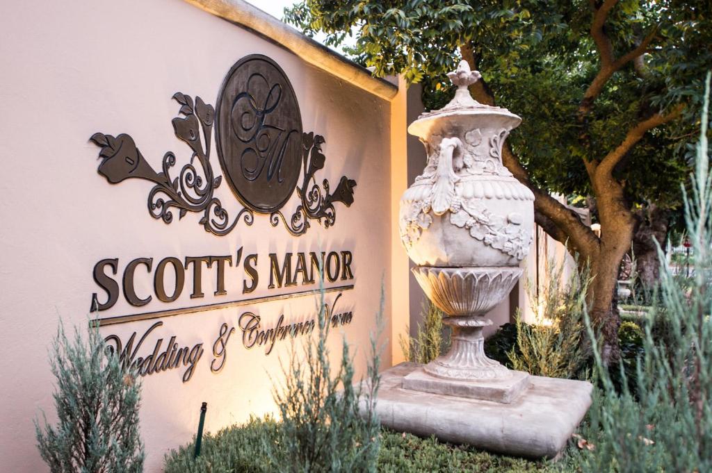 a sign for a garden with a vase in front of a building at Scott's Manor Guesthouse Function and Conference Venue in Lichtenburg