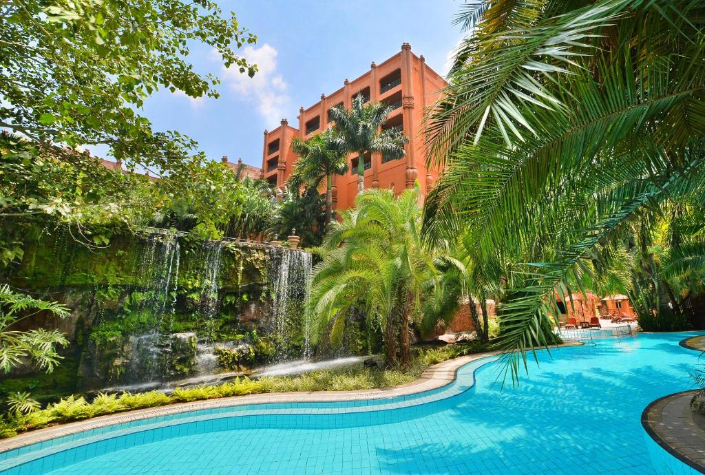 a swimming pool with a waterfall in front of a building at Kampala Serena Hotel in Kampala