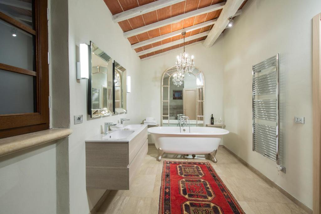 a bathroom with a tub and two sinks and a rug at Borgo Argiano in Castelnuovo Berardenga