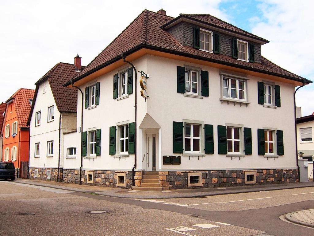 ein weißes Haus mit grünen Rollläden auf einer Straße in der Unterkunft Gasthof Schillereck in Lorsch