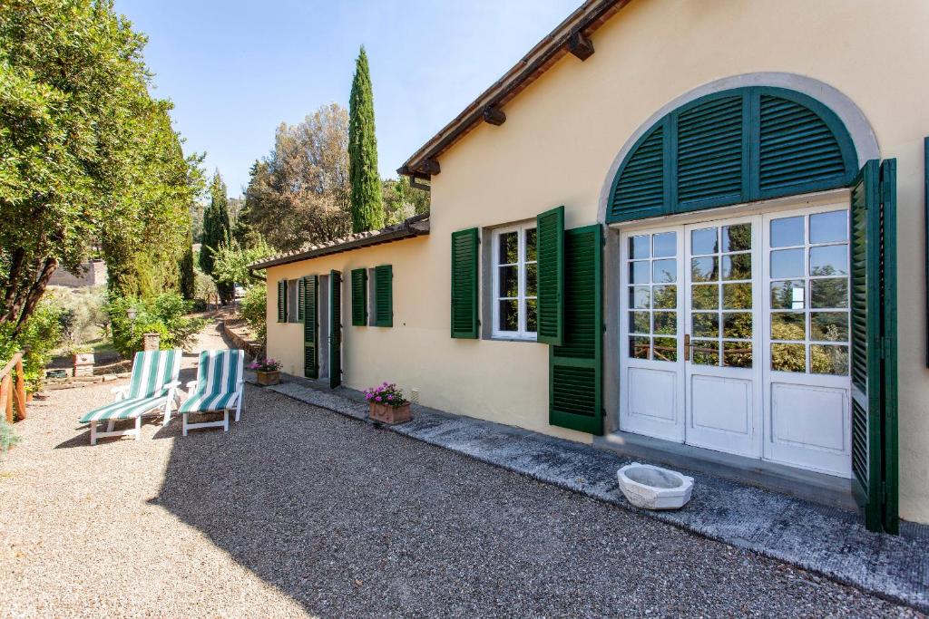 une maison avec des portes à volets verts et deux chaises dans l'établissement Villa Serena & Dépendances, à Cortone