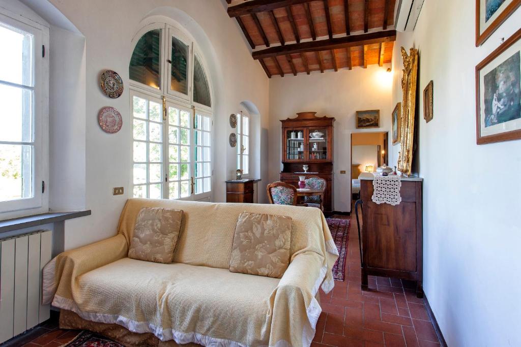 un salon avec un canapé et quelques fenêtres dans l'établissement Villa Serena & Dépendances, à Cortone