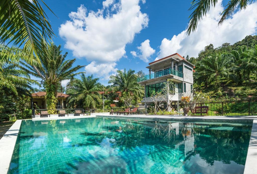 a villa with a swimming pool in front of a house at Krabi Green Hill Pool Villas in Ban Nong Thale