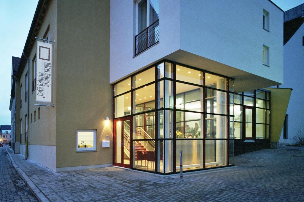 un edificio con grandes ventanas de cristal en una calle en Hôtel Galerie en Greifswald