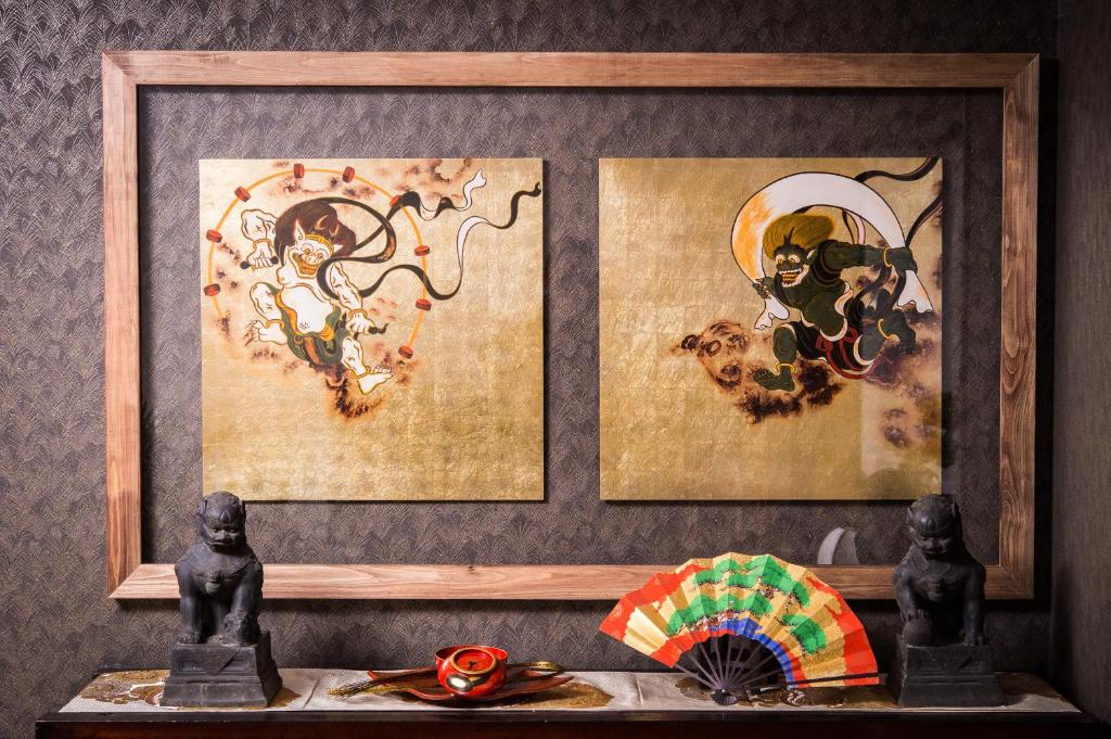 a shelf with two paintings and two figurines and an umbrella at Buddha House in Kyoto