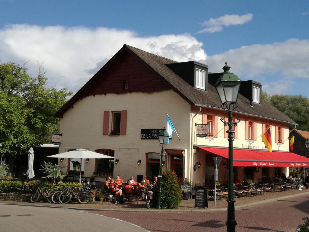 un groupe de personnes assis à l'extérieur d'un bâtiment dans l'établissement Herberg de la Frontière, à Slenaken