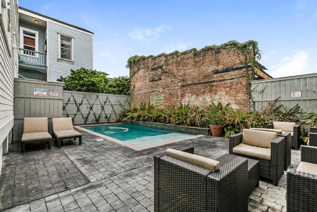a backyard with a pool and chairs and a brick wall at Spacious 2BR in Prime Garden District Location w Pool in New Orleans