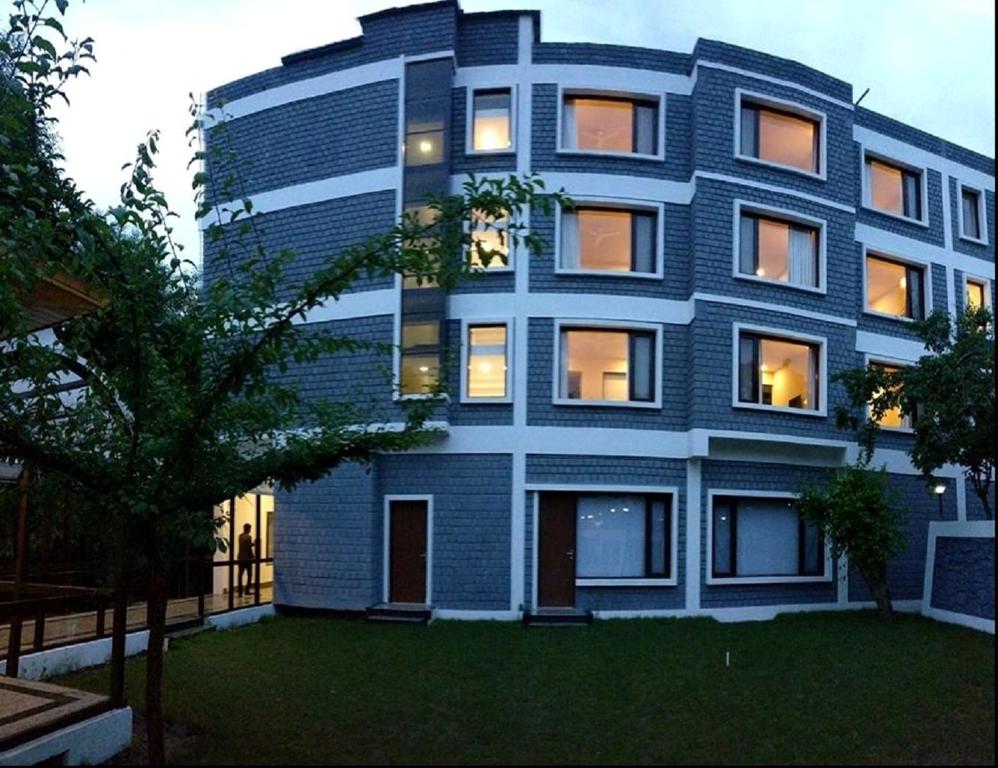 een blauw gebouw met een boom ervoor bij Hotel The Kargil in Kargil