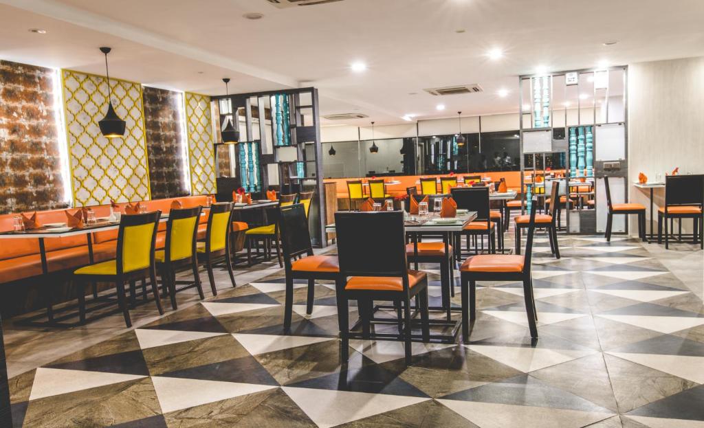 ein Restaurant mit gelben und schwarzen Stühlen und Tischen in der Unterkunft Kyriad Hotel Gulbarga by OTHPL in Gulbarga