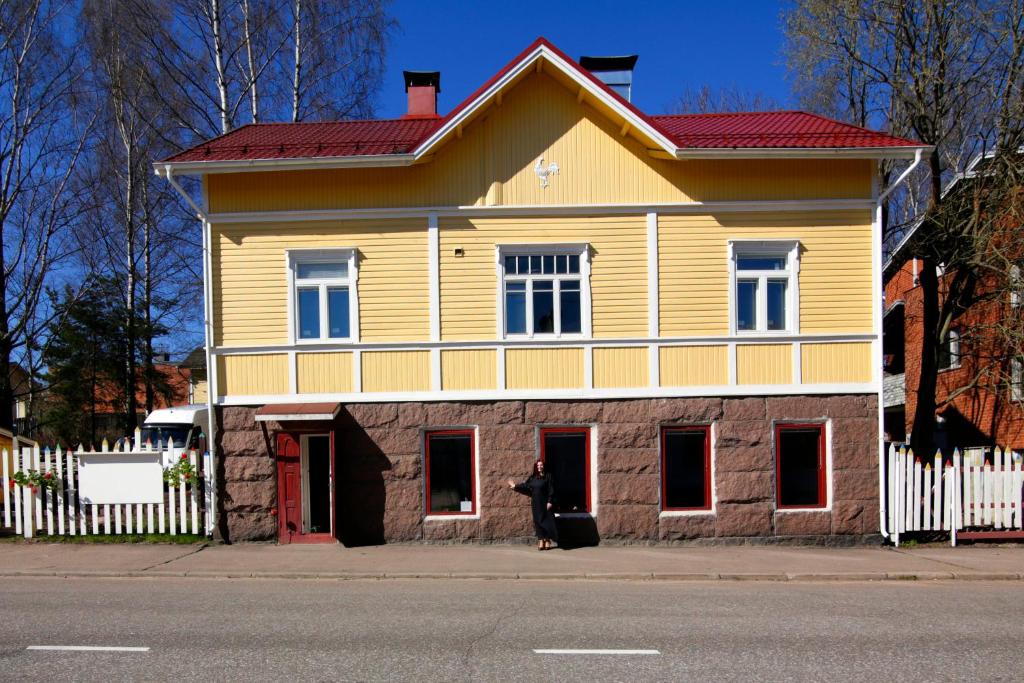 a large yellow and red house with a white fence at Guest House Nina Art in Kotka
