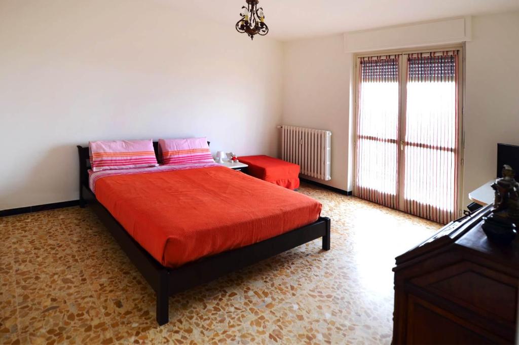 Schlafzimmer mit einem Bett mit roter Bettwäsche und einem Fenster in der Unterkunft Bene Vagienna Holiday House in Bene Vagienna
