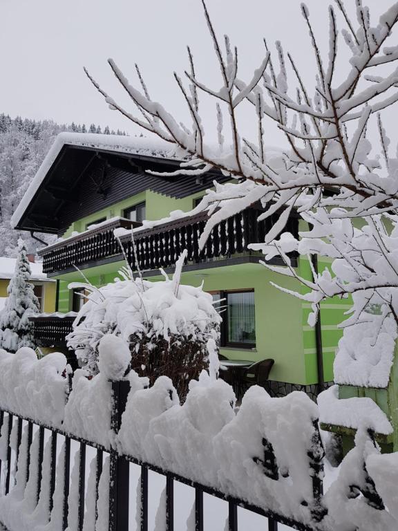 una cerca cubierta de nieve frente a una casa en Zeleni apartma Zreče, en Zreče