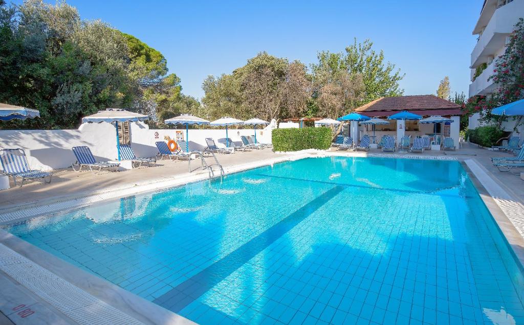 a large blue swimming pool with chairs and umbrellas at Hotel Nathalie in Ixia