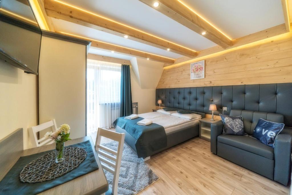 een slaapkamer met een bed, een bank en een tafel bij Pokoje U ŚLIWIOKA in Szaflary