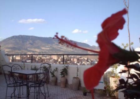 a patio with a table and chairs and a mountain at Dar Al Safadi in Fez