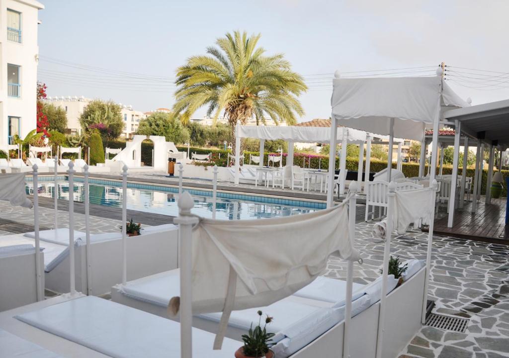 um resort com uma piscina e cadeiras brancas e uma piscina em Tasmaria Aparthotel em Pafos