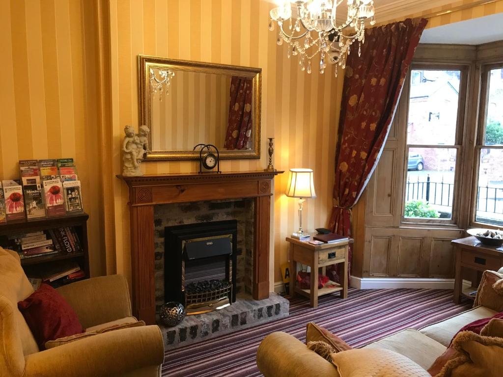 een woonkamer met een open haard en een spiegel bij Clayhanger Guest House in Newcastle under Lyme