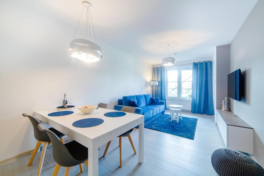 cocina y sala de estar con mesa blanca y sillas en DP Apartament Polanki Park, en Kołobrzeg