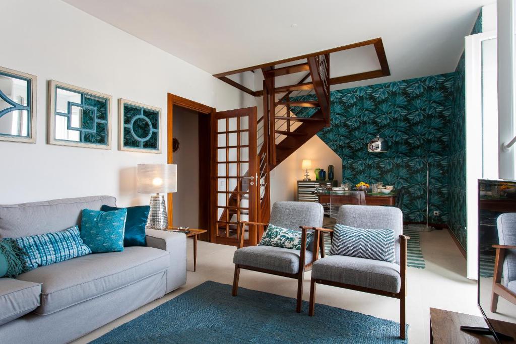 ein Wohnzimmer mit einem Sofa, Stühlen und einer Treppe in der Unterkunft bairro alto view point 3 bedrooms chalet in Lissabon