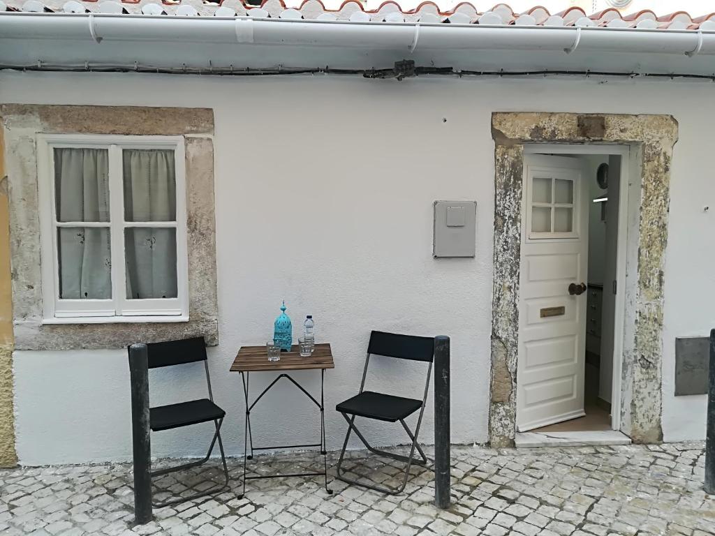 2 Stühle und ein Tisch vor einem weißen Gebäude in der Unterkunft Casinhas da Ajuda nº25 in Lissabon