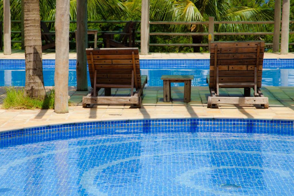 - deux chaises et une table à côté de la piscine dans l'établissement Pousada Armação dos Ventos, à Ilhabela