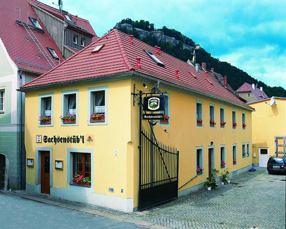 a yellow building with a red roof on a street at Sachsenstübel in Königstein an der Elbe