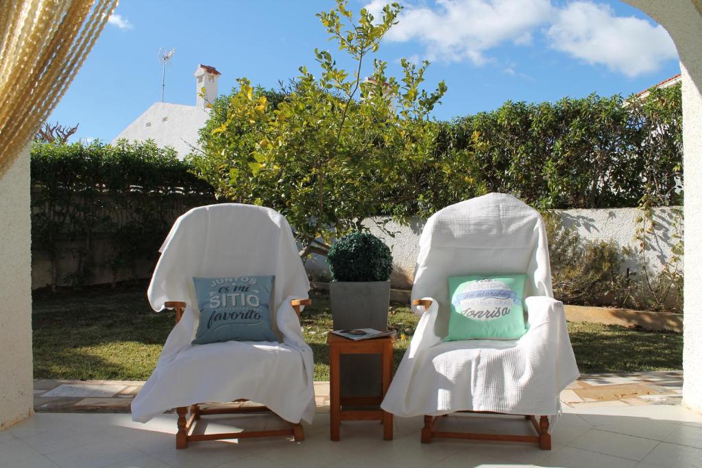 dwa białe krzesła siedzące obok siebie na patio w obiekcie Adosado Adelfas w mieście Peñíscola