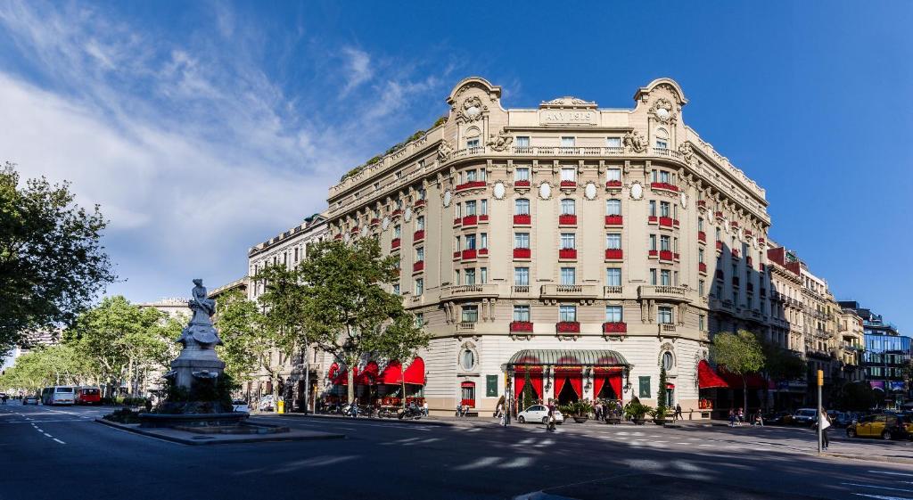 ein großes weißes Gebäude mit einer Statue davor in der Unterkunft Hotel El Palace Barcelona in Barcelona