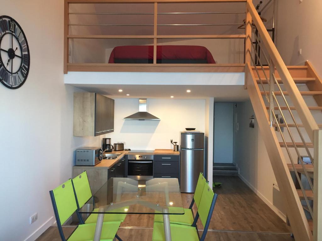 une cuisine avec une table en verre et des chaises vertes dans l'établissement Bel appartement vue sur mer, à Cancale