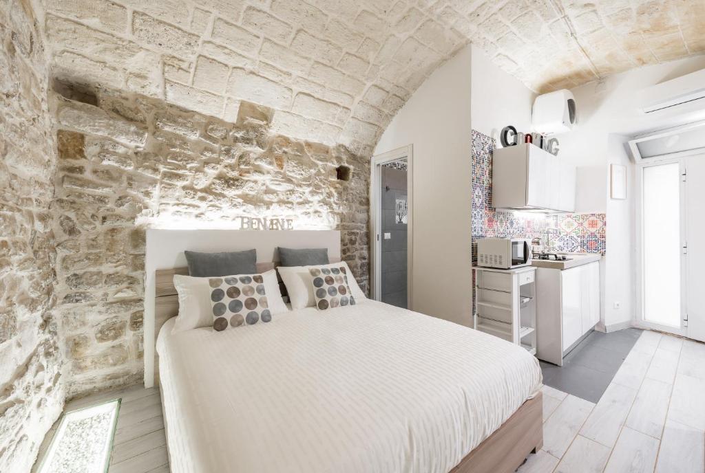 una camera con un grande letto e un muro di pietra di San Nicola Old Town Apartment a Bari
