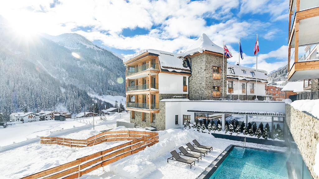 a building with a swimming pool in the snow at Mountain Spa Residences in Sankt Anton am Arlberg
