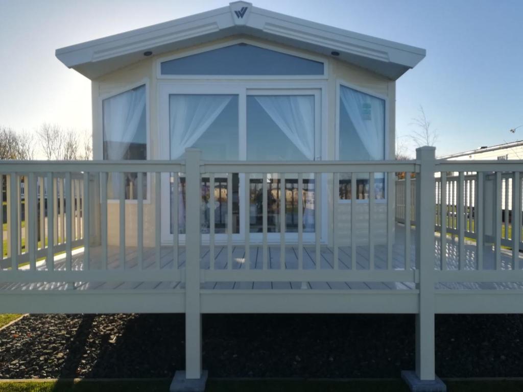 a screened in porch with a white fence at Aspen Retreat, Haggerston Castle in Cheswick