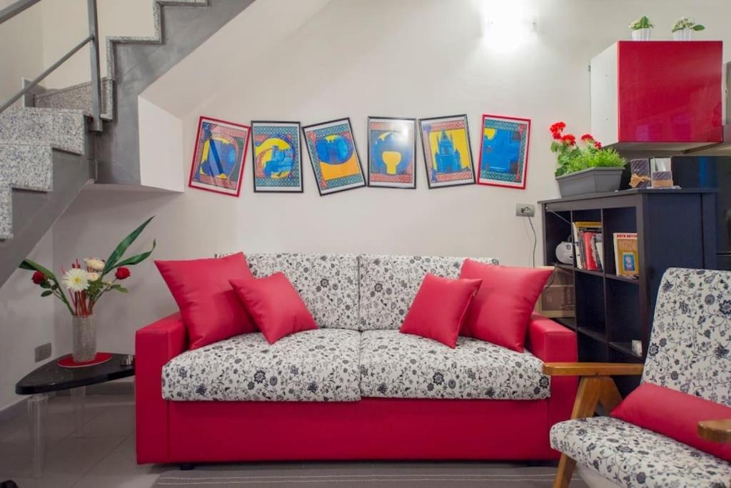 ein rotes Sofa im Wohnzimmer mit Gemälden an der Wand in der Unterkunft La Regina di Vertecoeli in Neapel