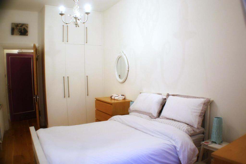 a bedroom with a bed with white sheets and a chandelier at The Lookout in Helensburgh