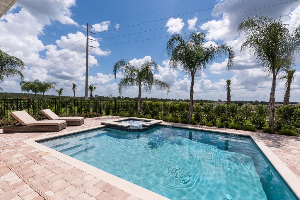 ein Pool mit Palmen im Hintergrund in der Unterkunft Luxury Dreams Disney Home with Private Pool and Spa in Orlando